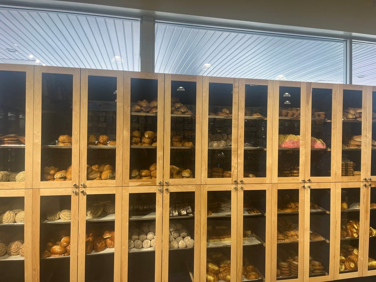 Glass-front wooden panadería cabinets full of pan dulce at Los Portales