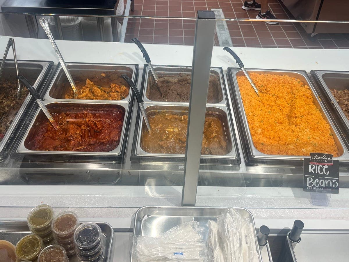 Steam table with rice, beans, and meats for catering at Los Portales