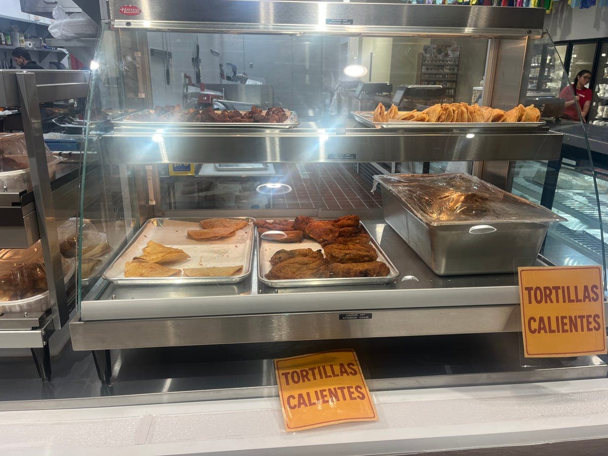 Hot food display with tamales and chicharrón at Los Portales